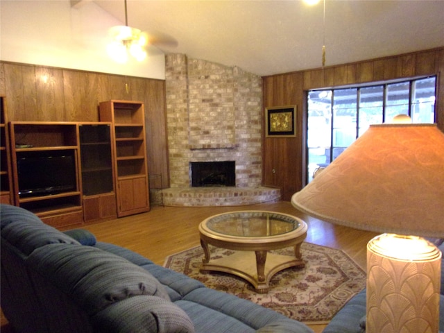 living room featuring wooden walls, a fireplace, vaulted ceiling, and wood-type flooring