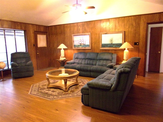 living room with wood-type flooring, wooden walls, vaulted ceiling, and ceiling fan