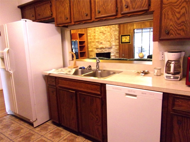 kitchen with light tile patterned floors, sink, kitchen peninsula, a brick fireplace, and white appliances