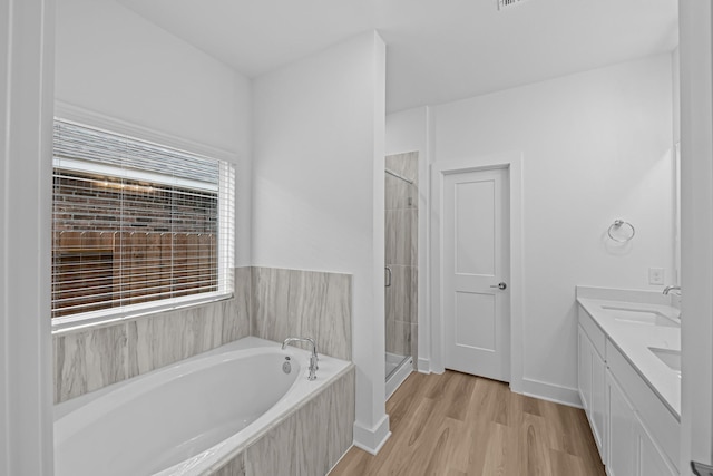 full bathroom featuring a garden tub, a sink, wood finished floors, a stall shower, and double vanity