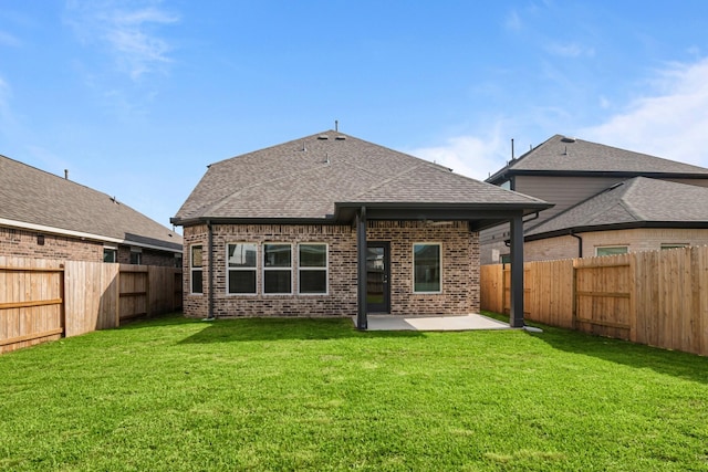 rear view of house with brick siding, roof with shingles, a fenced backyard, and a patio