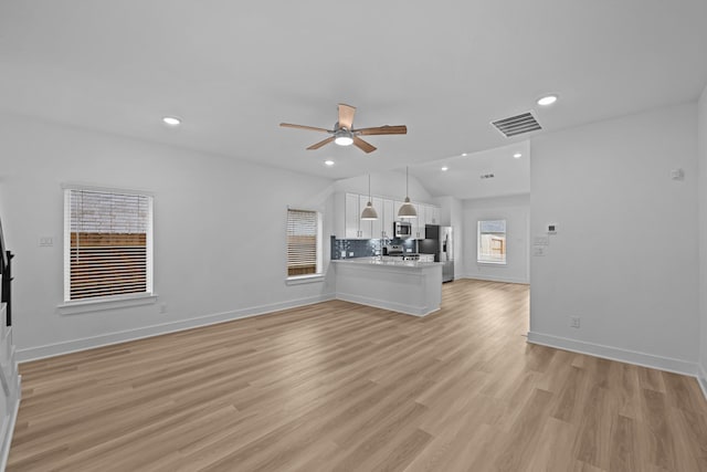 unfurnished living room featuring vaulted ceiling, visible vents, a ceiling fan, baseboards, and light wood-style flooring