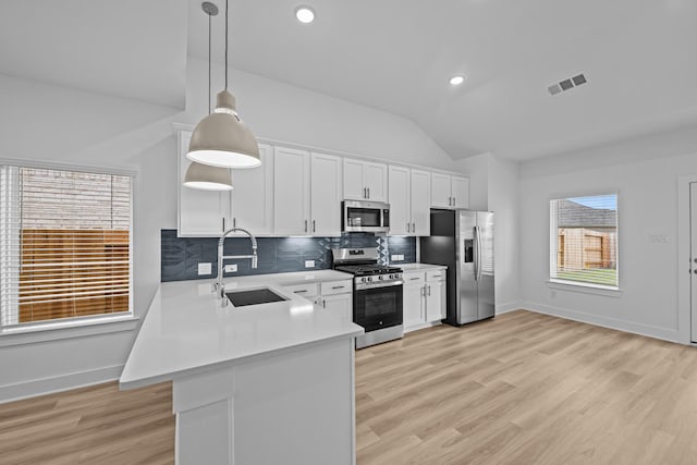 kitchen with light countertops, vaulted ceiling, visible vents, a sink, and appliances with stainless steel finishes