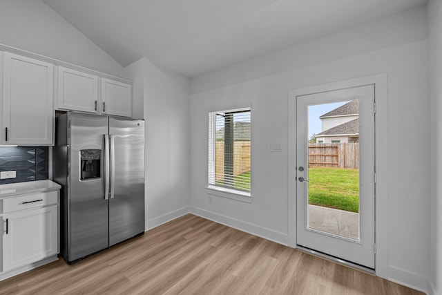 kitchen featuring white cabinets, stainless steel refrigerator with ice dispenser, light wood finished floors, and lofted ceiling