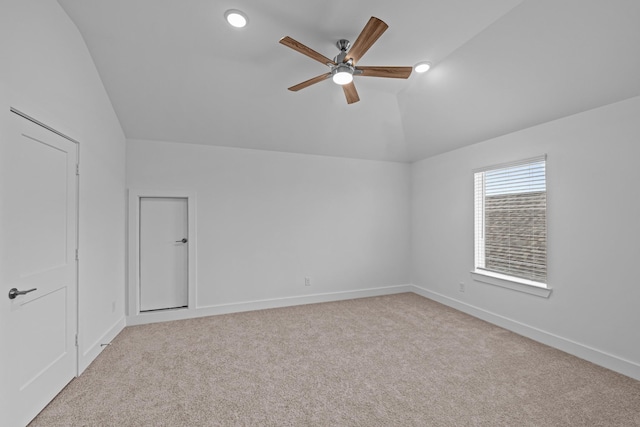 carpeted empty room with vaulted ceiling, baseboards, and ceiling fan