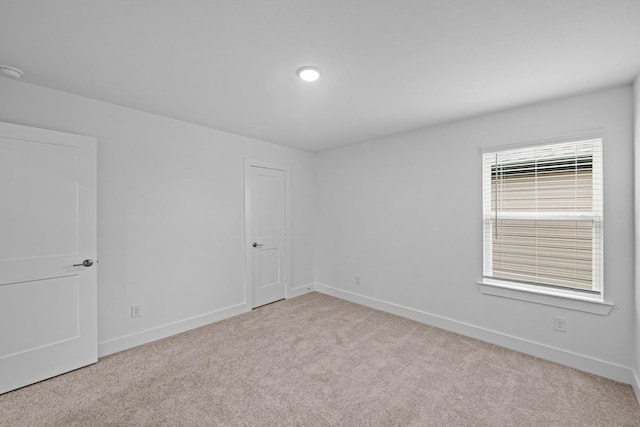 carpeted empty room featuring baseboards