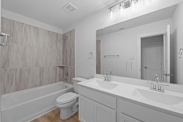 bathroom with toilet, wood finished floors, a sink, and visible vents