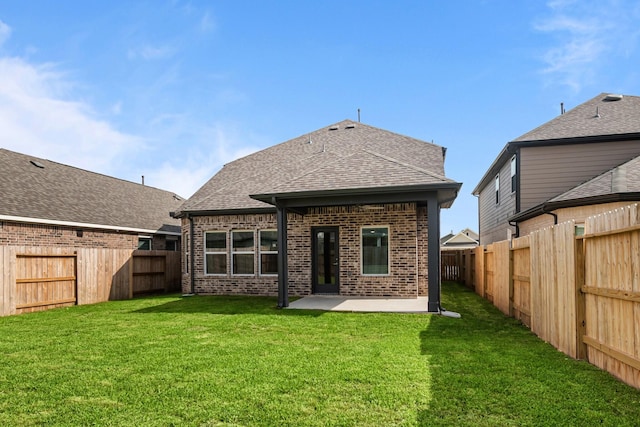 rear view of property with a lawn, brick siding, a patio area, and a fenced backyard