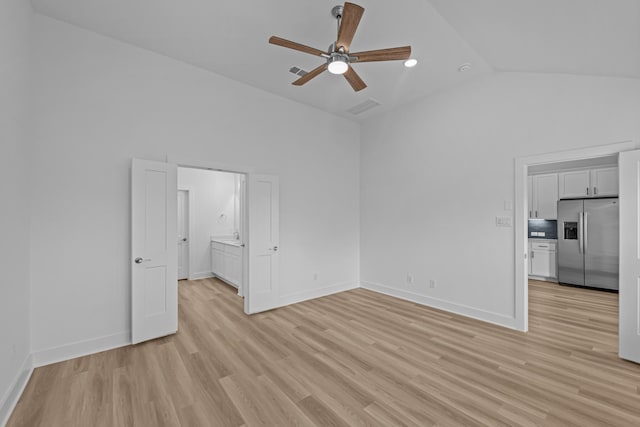 unfurnished bedroom with light wood finished floors, vaulted ceiling, visible vents, baseboards, and stainless steel refrigerator with ice dispenser
