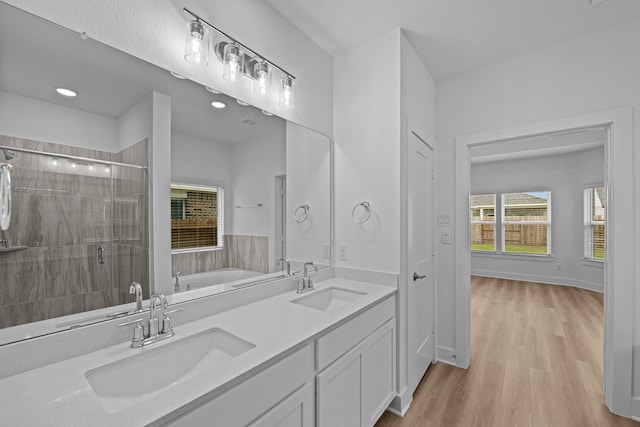 bathroom with a bath, wood finished floors, a sink, and a stall shower