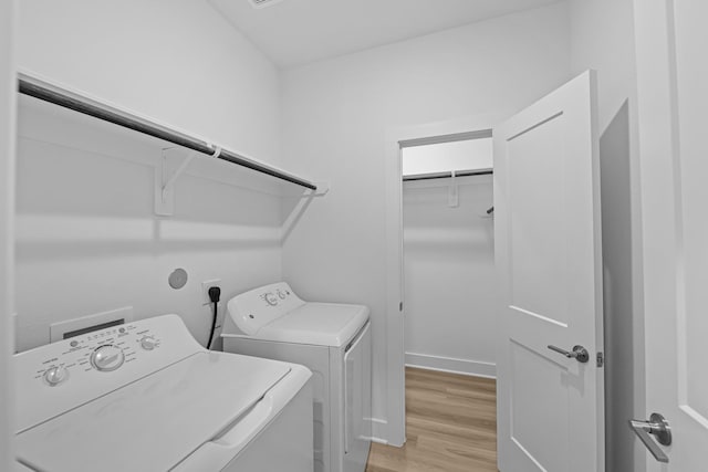 clothes washing area featuring washing machine and clothes dryer, laundry area, and light wood-type flooring