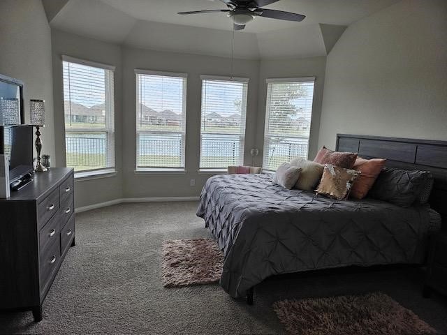 carpeted bedroom with ceiling fan, a water view, lofted ceiling, and multiple windows