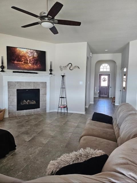 living room with ceiling fan and a tiled fireplace