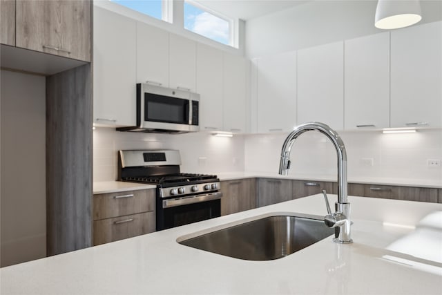 kitchen featuring white cabinetry, appliances with stainless steel finishes, sink, and backsplash