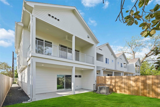 rear view of property featuring central AC unit, a balcony, a yard, and a patio area