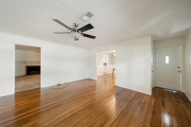 unfurnished living room featuring ceiling fan, a textured ceiling, and dark wood-type flooring