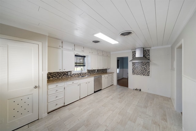 kitchen featuring white cabinets, wood walls, stainless steel dishwasher, wall chimney range hood, and light wood-type flooring