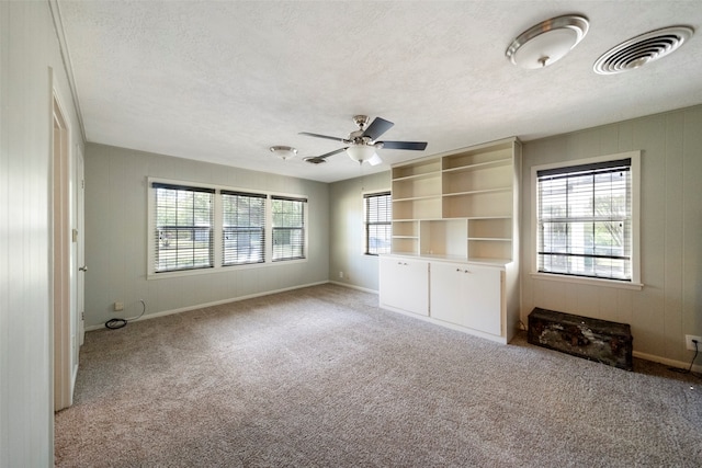 unfurnished living room with light colored carpet, a textured ceiling, and a healthy amount of sunlight