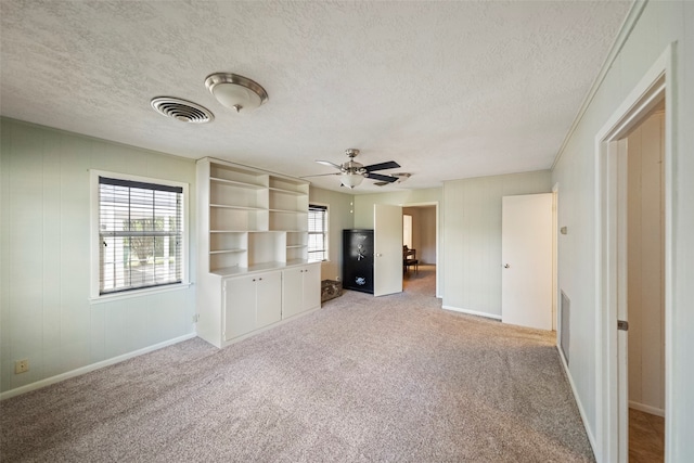 unfurnished living room with ceiling fan, light carpet, and a textured ceiling