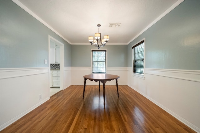 unfurnished dining area with a notable chandelier, ornamental molding, and hardwood / wood-style flooring