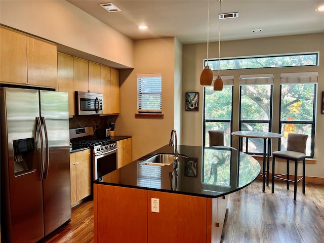 kitchen with a center island with sink, appliances with stainless steel finishes, sink, and wood-type flooring