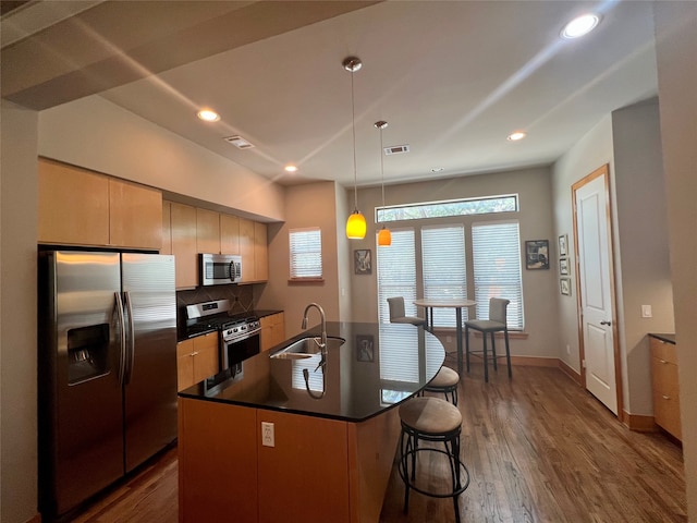 kitchen featuring hanging light fixtures, a center island with sink, sink, dark hardwood / wood-style floors, and appliances with stainless steel finishes