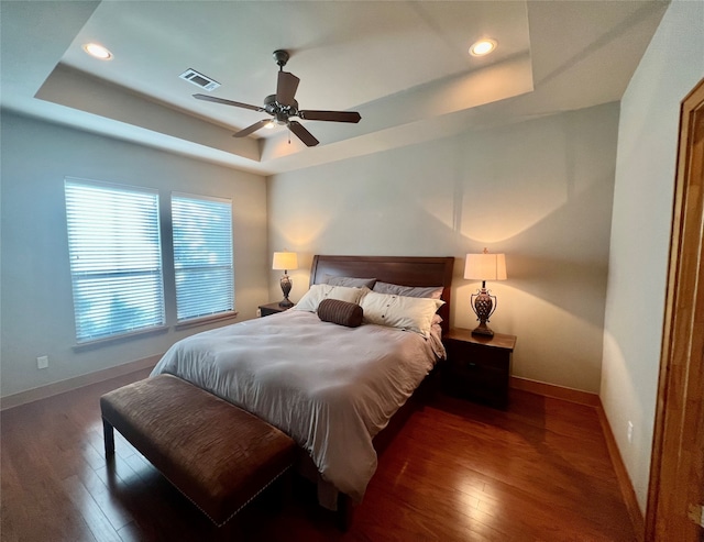 bedroom featuring ceiling fan, a raised ceiling, and dark hardwood / wood-style flooring