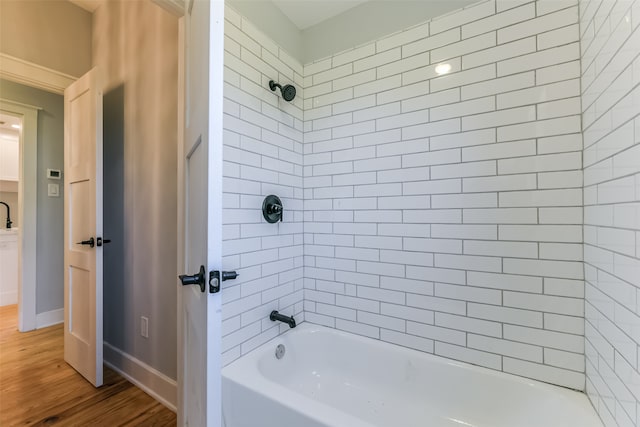 bathroom with hardwood / wood-style flooring and tiled shower / bath