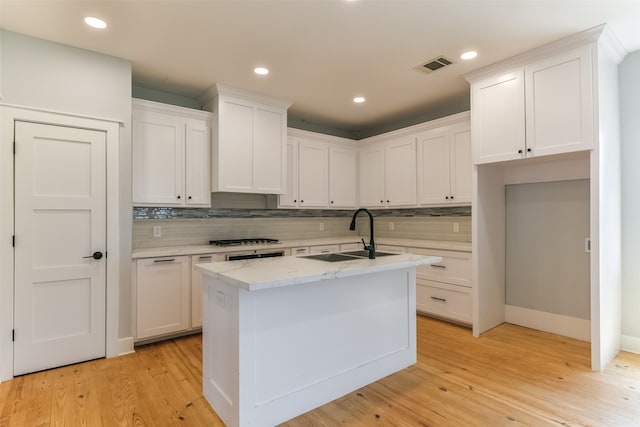 kitchen featuring light hardwood / wood-style flooring, a center island with sink, sink, decorative backsplash, and white cabinets