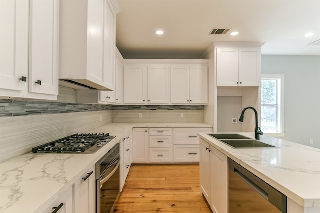 kitchen featuring stainless steel appliances, white cabinets, sink, and light wood-type flooring