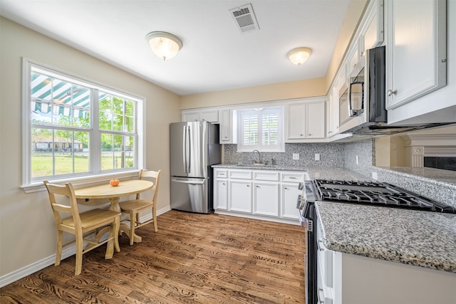 kitchen with white cabinetry, wood-type flooring, sink, light stone counters, and stainless steel appliances