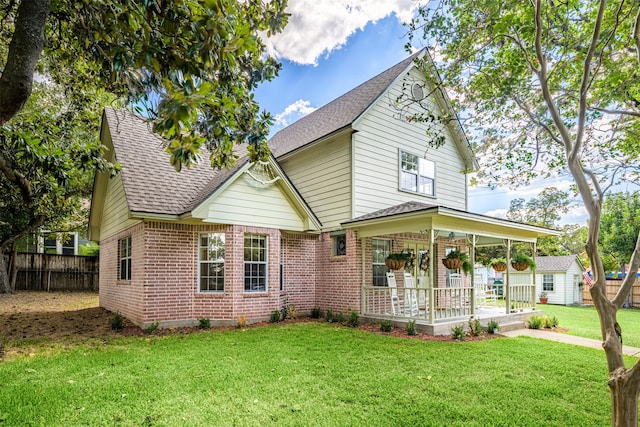 view of front of house with a porch, a front lawn, and a storage shed