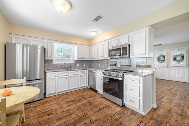 kitchen featuring sink, white cabinetry, dark hardwood / wood-style flooring, stainless steel appliances, and light stone countertops