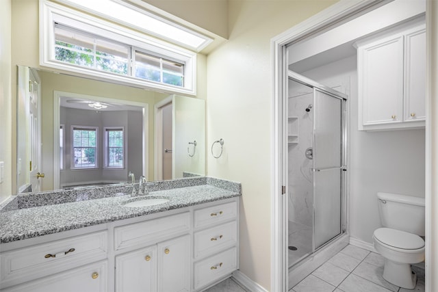 bathroom with a shower with door, vanity, tile patterned floors, and toilet