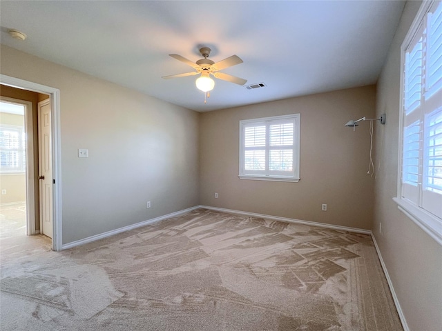 carpeted empty room with ceiling fan and plenty of natural light