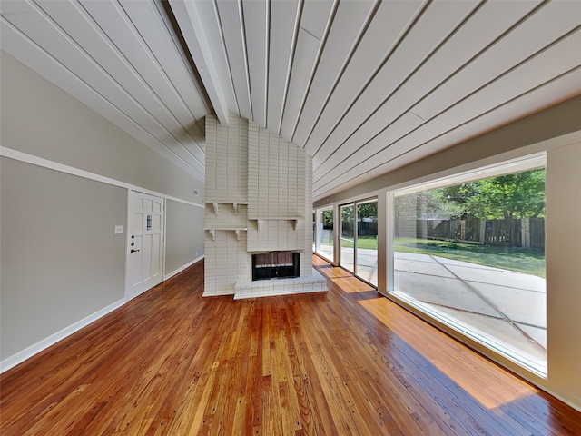 unfurnished living room with vaulted ceiling with beams, a fireplace, and hardwood / wood-style floors