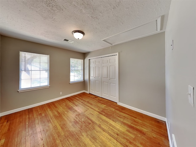 unfurnished bedroom featuring hardwood / wood-style flooring, a closet, and a textured ceiling