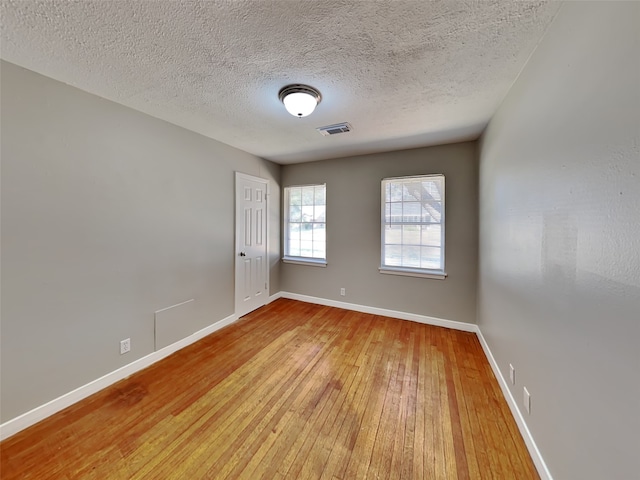 spare room featuring a textured ceiling and light wood-type flooring