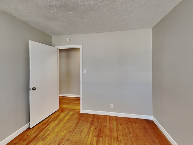 empty room with hardwood / wood-style flooring and a textured ceiling