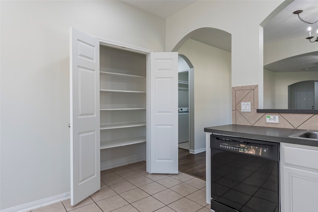 kitchen with white cabinets, tasteful backsplash, light tile patterned floors, a notable chandelier, and dishwasher