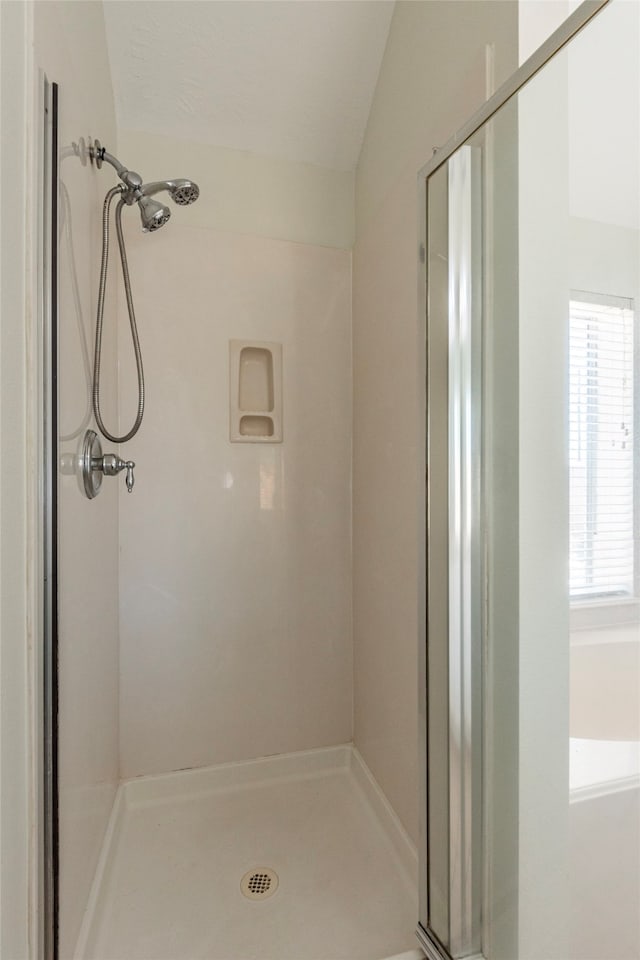 bathroom featuring tiled shower and lofted ceiling