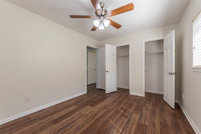 unfurnished bedroom featuring dark hardwood / wood-style flooring, ceiling fan, and multiple closets