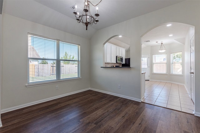 interior space with vaulted ceiling, dark hardwood / wood-style flooring, and an inviting chandelier