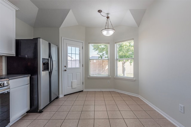 kitchen with lofted ceiling, white cabinets, light tile patterned floors, and appliances with stainless steel finishes