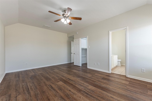 unfurnished bedroom with a walk in closet, lofted ceiling, dark hardwood / wood-style floors, and ensuite bath