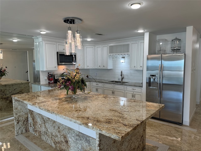 kitchen with light stone counters, white cabinets, sink, decorative light fixtures, and appliances with stainless steel finishes