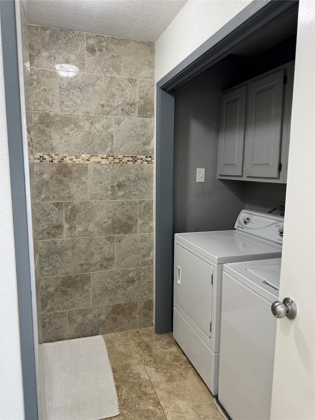 laundry room with a textured ceiling, independent washer and dryer, and cabinets