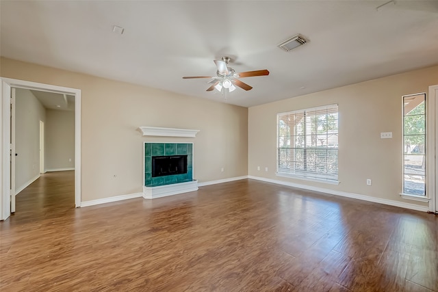 unfurnished living room with ceiling fan, a fireplace, hardwood / wood-style flooring, and plenty of natural light