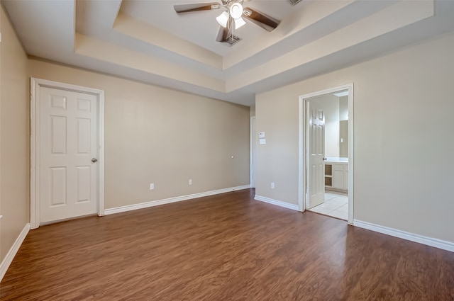 empty room with ceiling fan, hardwood / wood-style flooring, and a raised ceiling