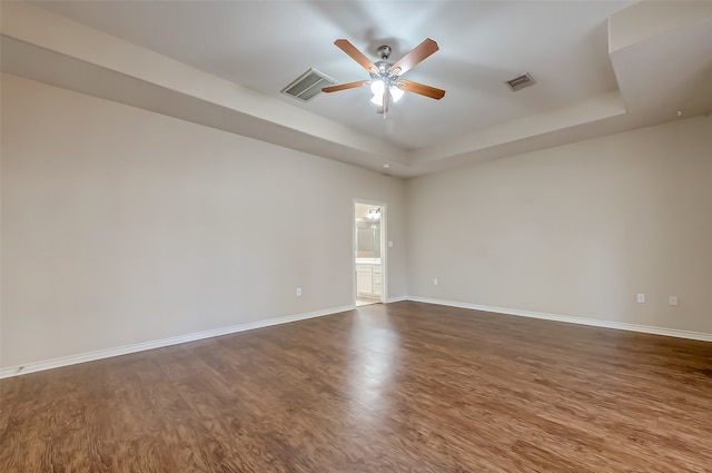 spare room with hardwood / wood-style floors, ceiling fan, and a raised ceiling